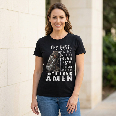 Woman wearing the black Until I Said Amen Christian graphic T-shirt with blue jeans beside a cream stone wall.